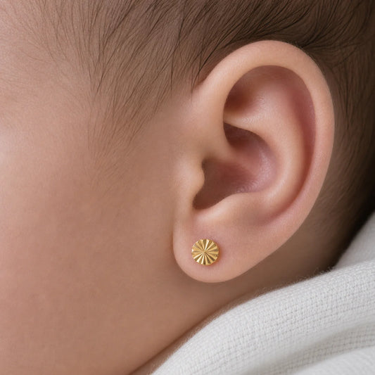 Detalle de la oreja de una recién nacida luciendo un aro abridor redondo facetado de oro 18k de 4mm. El tamaño es proporcional y delicado, resaltando el brillo del oro macizo con seguridad.