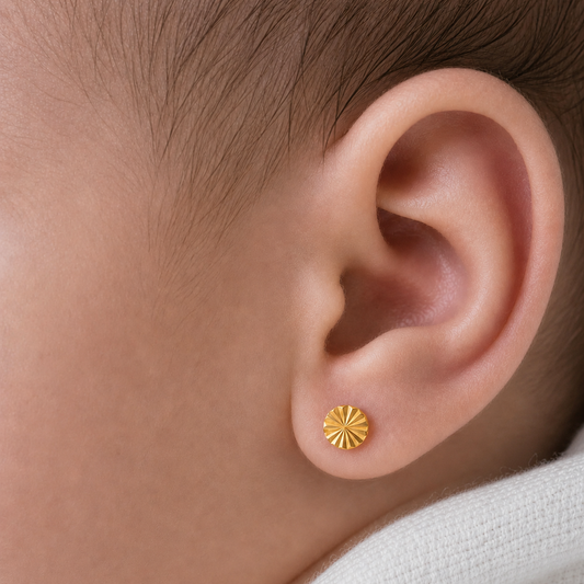 Detalle de la oreja de una recién nacida luciendo un aro abridor redondo facetado de oro 18k de 4mm. El tamaño es proporcional y delicado, resaltando el brillo del oro macizo con seguridad.