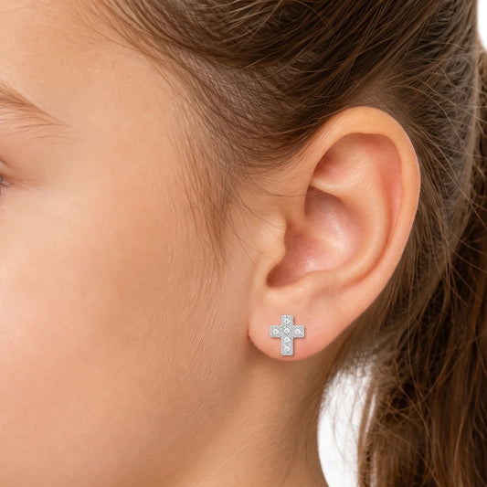 aros cruz con circones puestos en la oreja de una niña de 6 años
