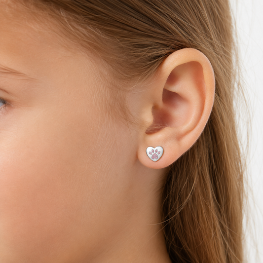 Niña luciendo los aros de corazón con huella de perrito y circones rosados en plata ley 925