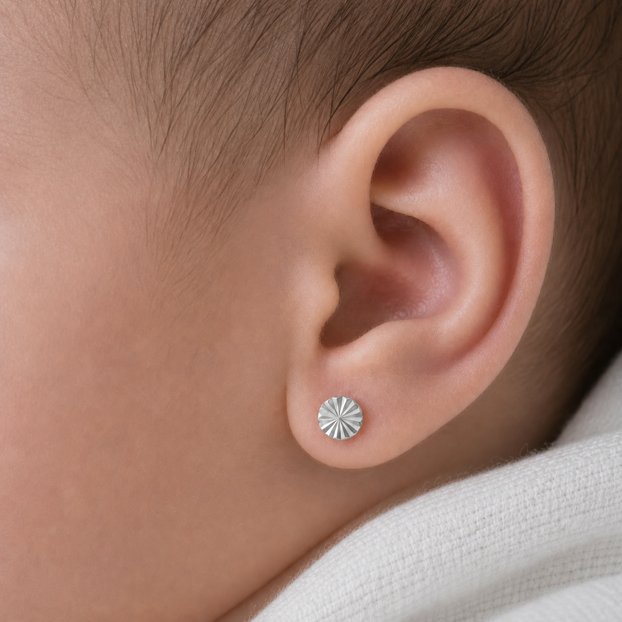Abridor de plata ley 925 modelo facetado puesto en la oreja de una bebé