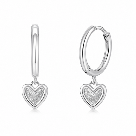 Par de aros argolla de plata ley 925 para niña de 12mm de diámetro con un colgante en forma de corazón de 6x6mm con centro texturizado brillante, sobre un fondo blanco.