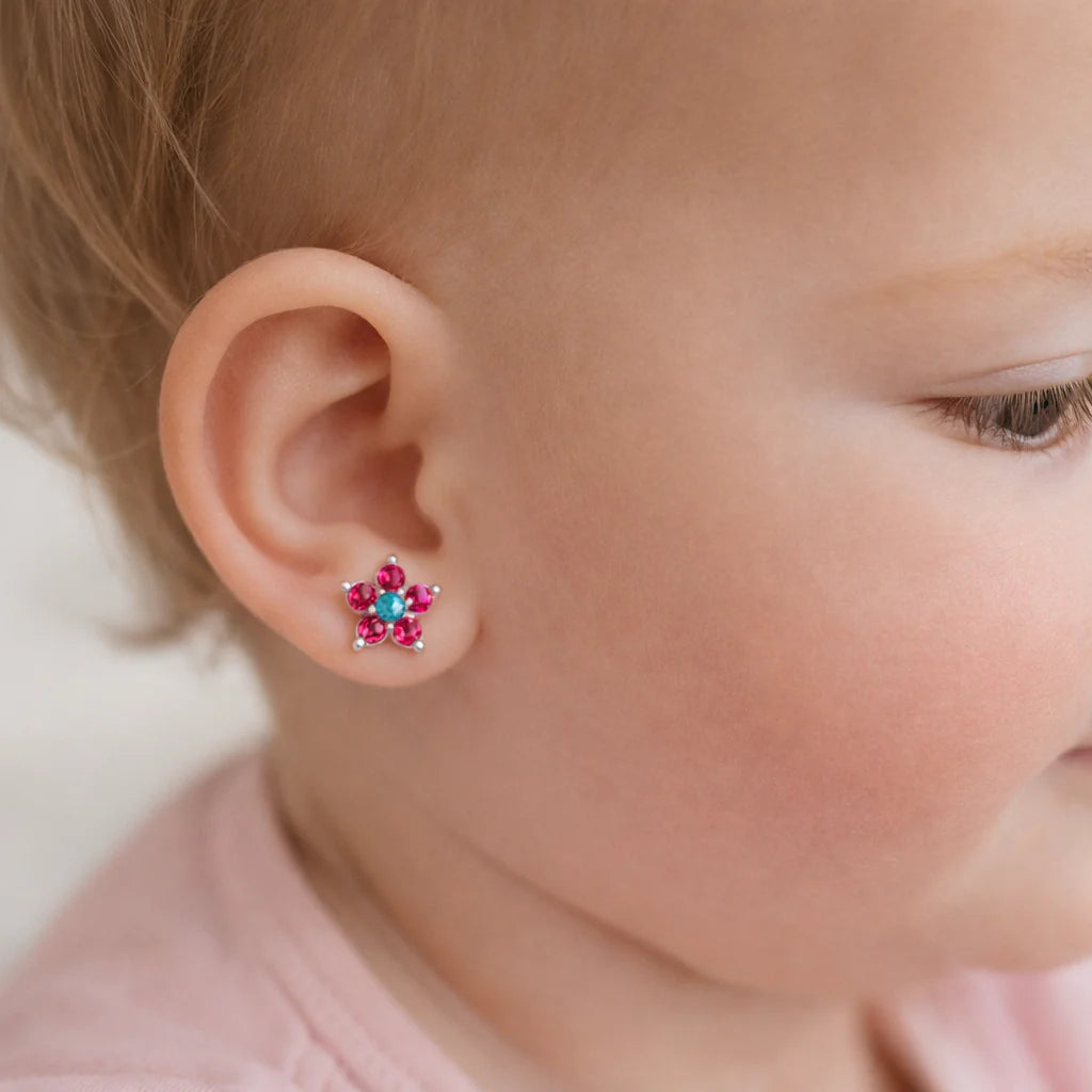 "Niña de un año usando aros de flor multicolor en plata 925, mostrando el contraste de los circones fucsias y el tamaño de 6mm."