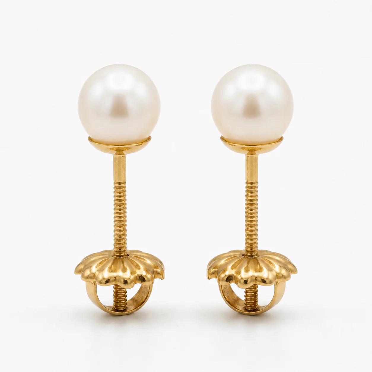 Par de aros de oro macizo 18k con perlas cultivadas de 6mm, vistos de frente sobre un fondo blanco, destacando el brillo del oro amarillo y la forma circular de las perlas.