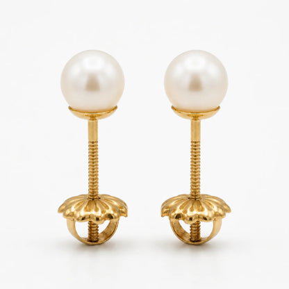 Par de aros de oro macizo 18k con perlas cultivadas de 6mm, vistos de frente sobre un fondo blanco, destacando el brillo del oro amarillo y la forma circular de las perlas.