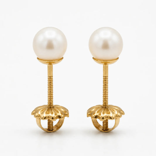 Par de aros de oro macizo 18k con perlas cultivadas de 6mm, vistos de frente sobre un fondo blanco, destacando el brillo del oro amarillo y la forma circular de las perlas.