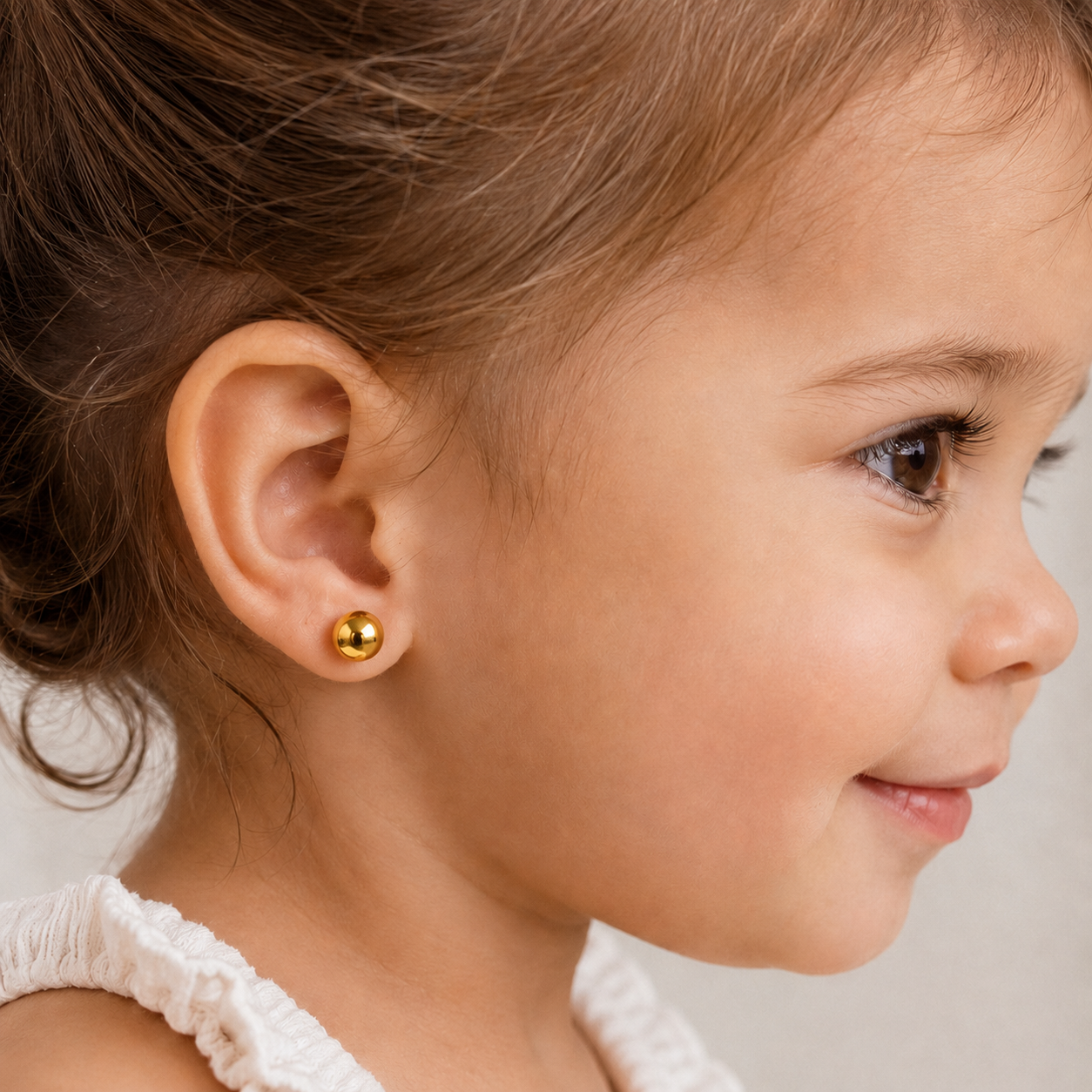 Niña de 3 años usando aros de oro 18k bolita de 6 mm puestos en la oreja