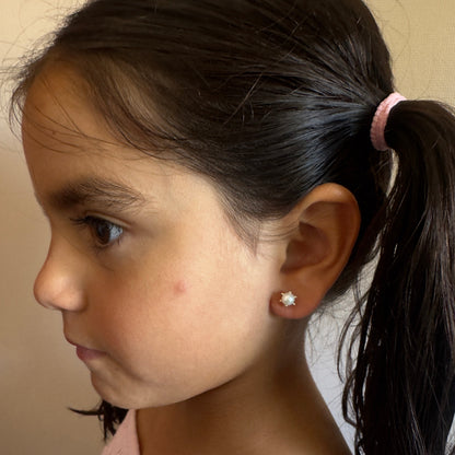 "Niña de 6 años luciendo aros de oro 18k modelo pistilo con perla cultivada, destacando el tamaño proporcional de 7mm y el ajuste seguro y cómodo en la oreja."