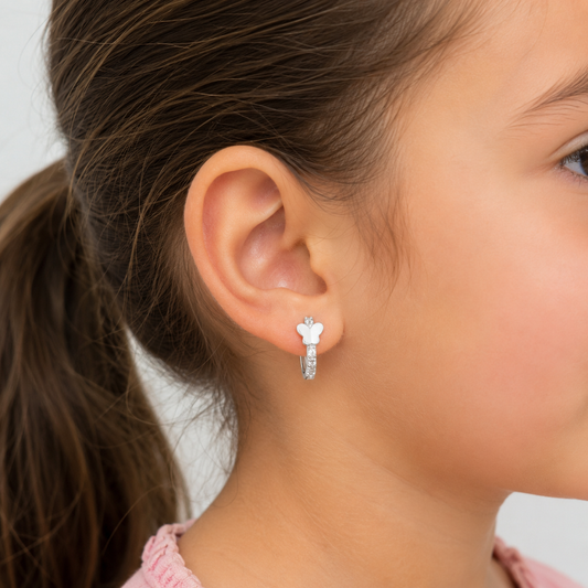 Niña de 6 años usando un aro argolla de plata 925 con una pequeña mariposa y circones, mostrando el tamaño de la joya de 13mm de forma segura y delicada en su oreja.