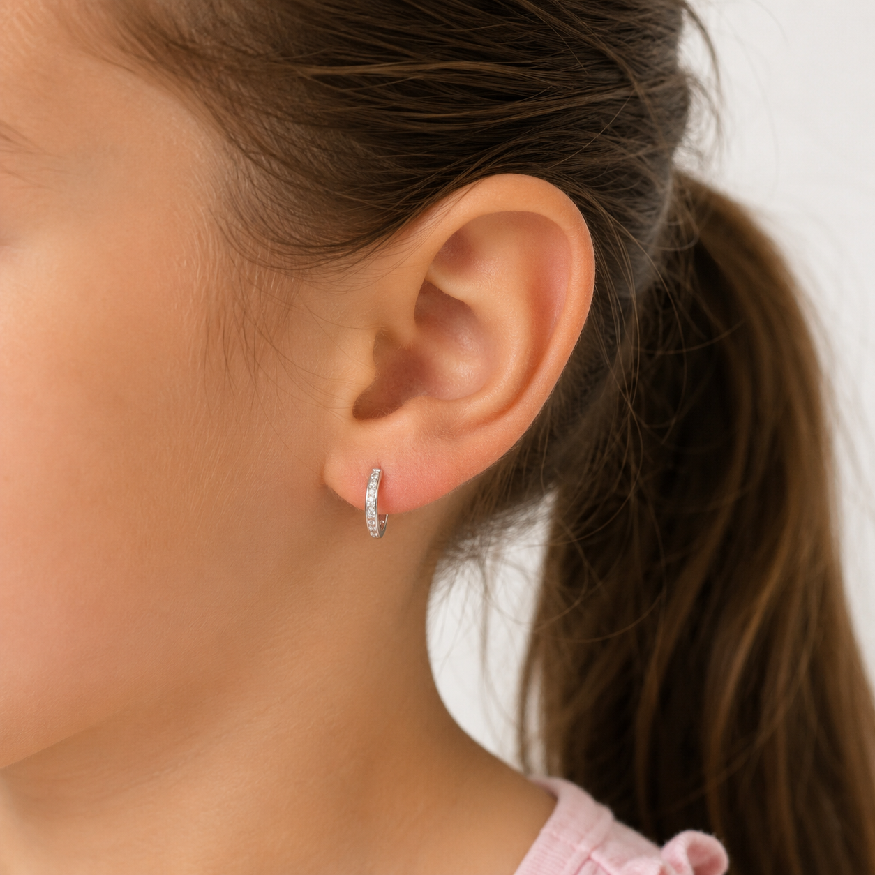 Niña de 6 años luciendo un aro argolla de plata de 12mm con circones pequeños brillantes, mostrando cómo queda el tamaño de la joya de manera delicada y segura en su oreja.