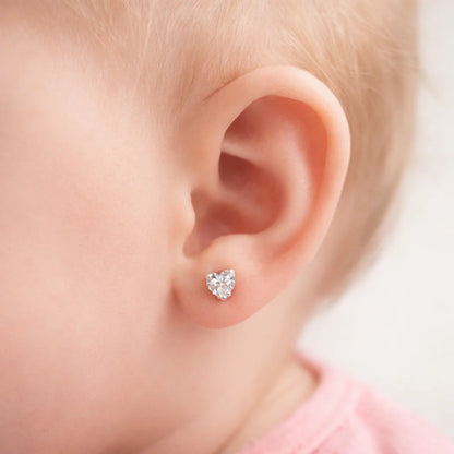 "Aro de corazón con circón de 4mm puesto en la oreja de una bebé de 6 meses para mostrar escala y tamaño."