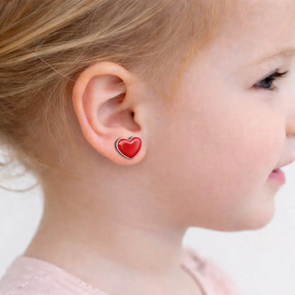 "Vista lateral de aro de corazón rojo de 7mm puesto en niña de 3 años, resaltando el color intenso y el ajuste cómodo en el lóbulo."