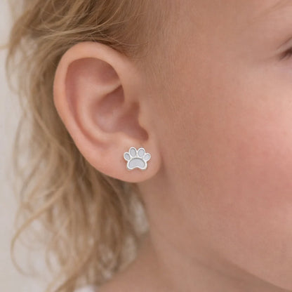 "Detalle de una niña de 3 años luciendo un tierno aro de plata 925 con diseño de patita blanca esmaltada que destaca con un brillo sutil en su oreja."
