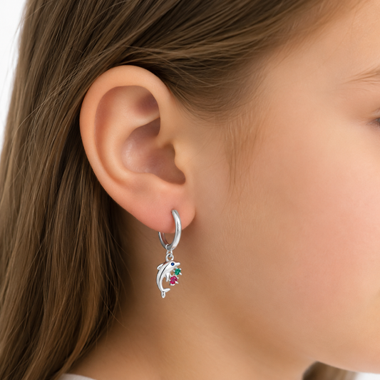 Aros de argolla con dije de delfín en plata ley 925 puestos en una niña