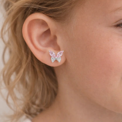 "Primer plano de una niña de 6 años luciendo unos brillantes aros de mariposa en plata 925 con detalles en circones rosa que resaltan en su oreja."