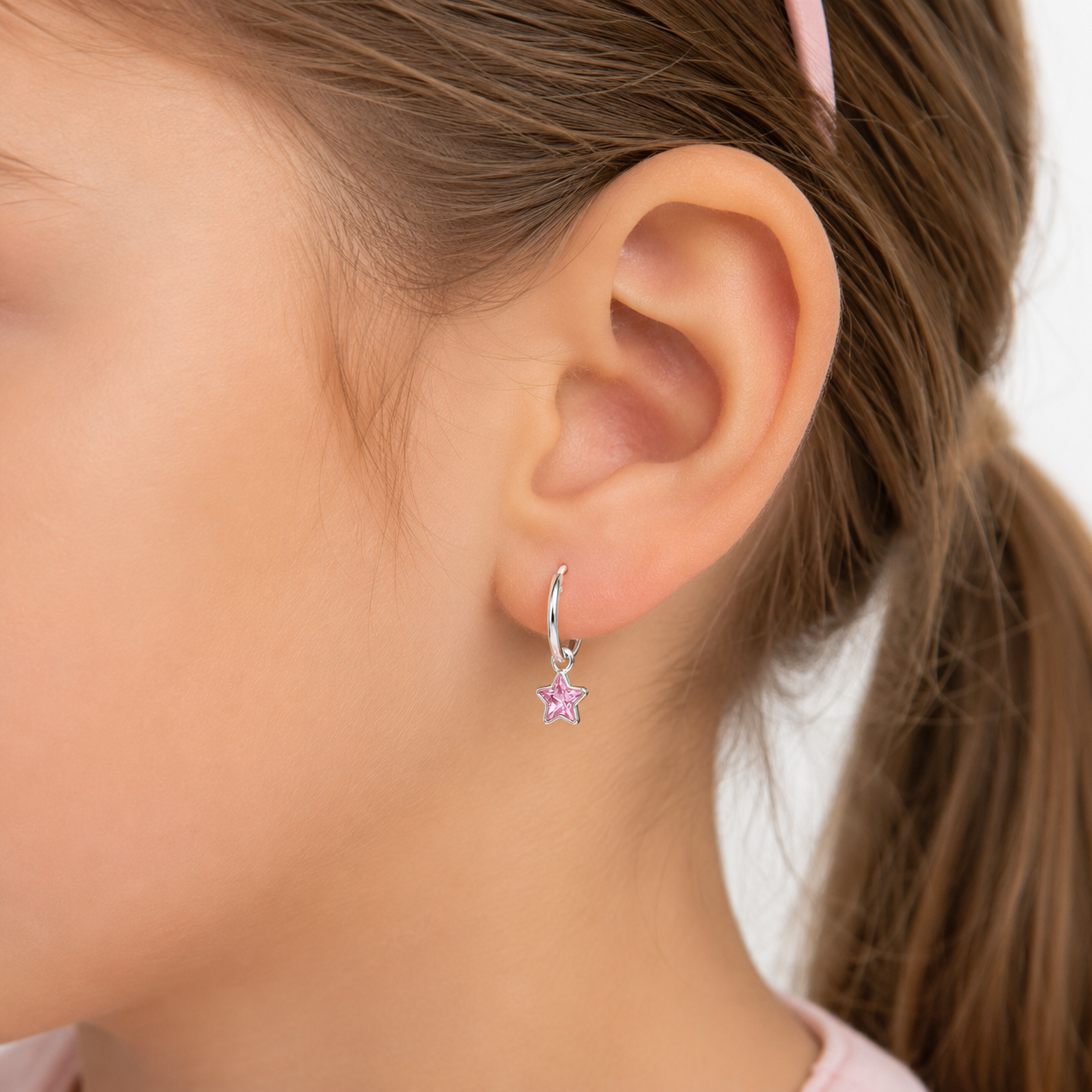 Argollas de plata ley 925 con dije de estrella rosa, puestos en una niña de 6 años